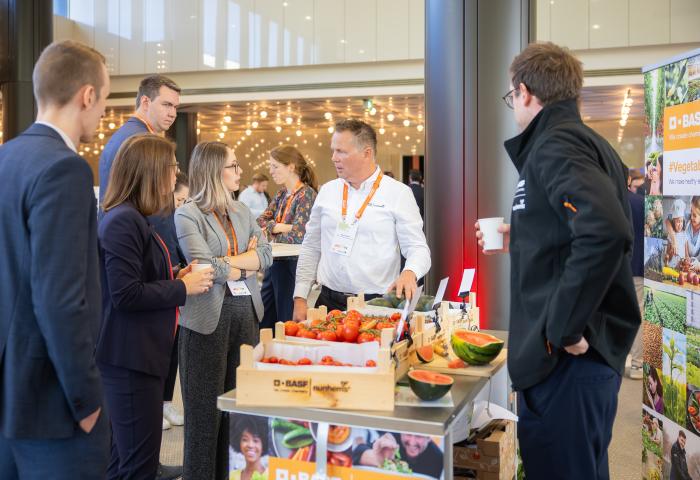 Personen stehen um Tisch mit Obst und Gemüse und sind im Gespräch