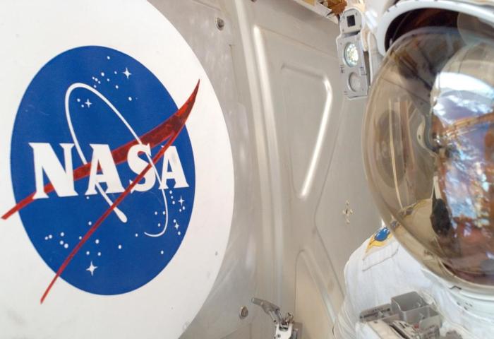 Der Helm eines Astronauten neben dem NASA-Logo.