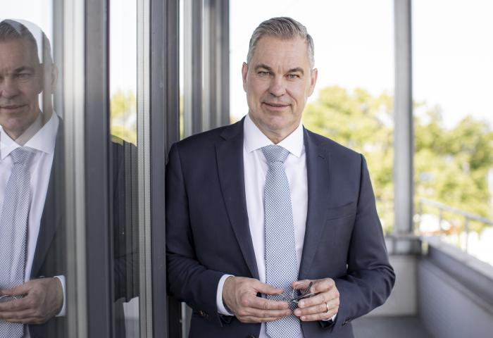 Ein Mann mit weißem Hemd und hellblauer Krawatte und dunkelblauer Jacke.