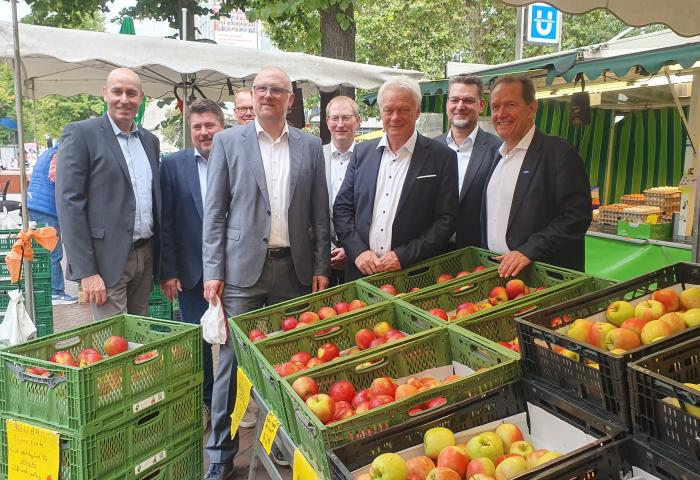 Männer stehen an einem Marktstand vor Äpfeln