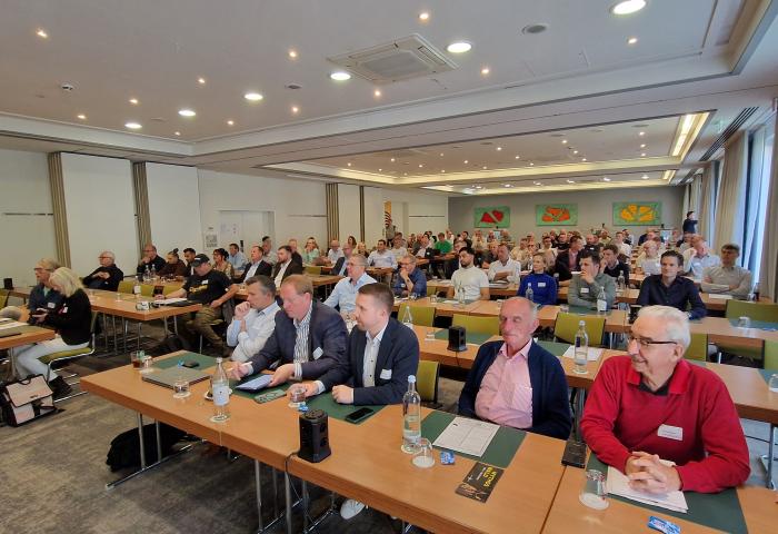 Zahlreiche Teilnehmende sitzen während einer Fachtagung in einem großen Konferenzraum.