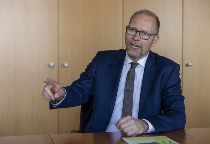 Mann sitzt mit erhobenem Zeigefinger am Tisch