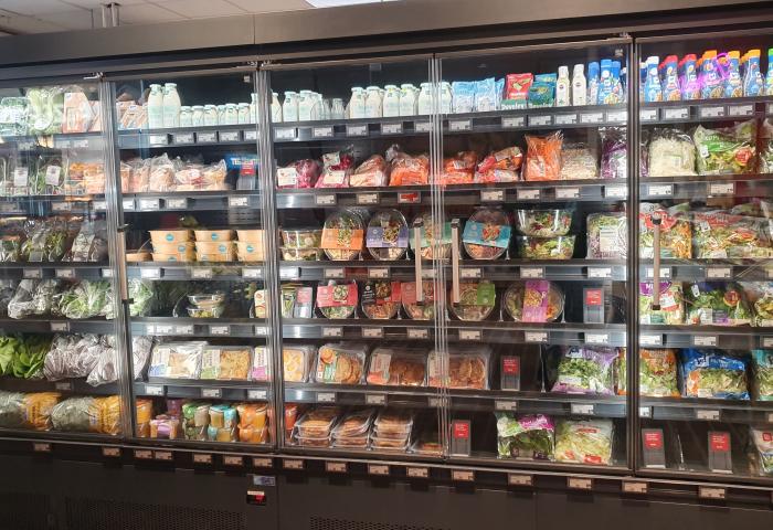Kühlregal im Lebensmitteleinzelhandel mit verpackten Salaten, Gemüse und weiteren Convenience-Produkten.