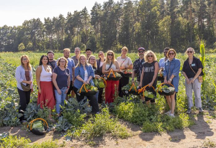 Männer und Frauen mit Gemüse gefüllten Körben auf Feld