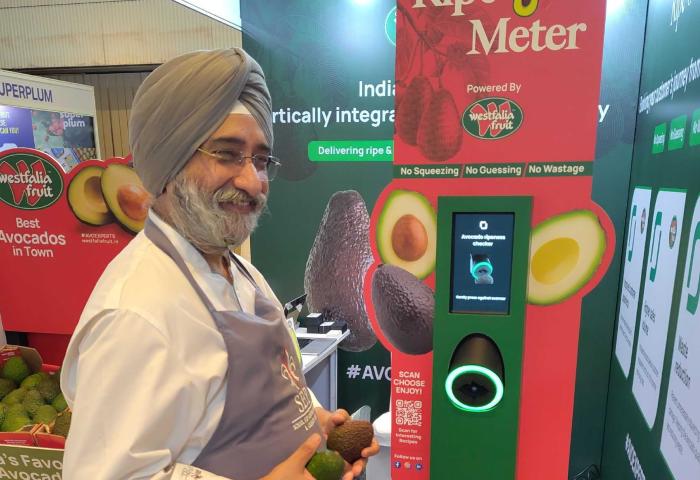 Mann steht mit Avocado vor Automat