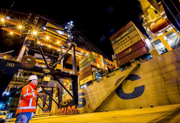 Mitarbeiter im Hafen Rotterdam vor einem Containerschiff beim nächtlichen Umschlag von Containern.
