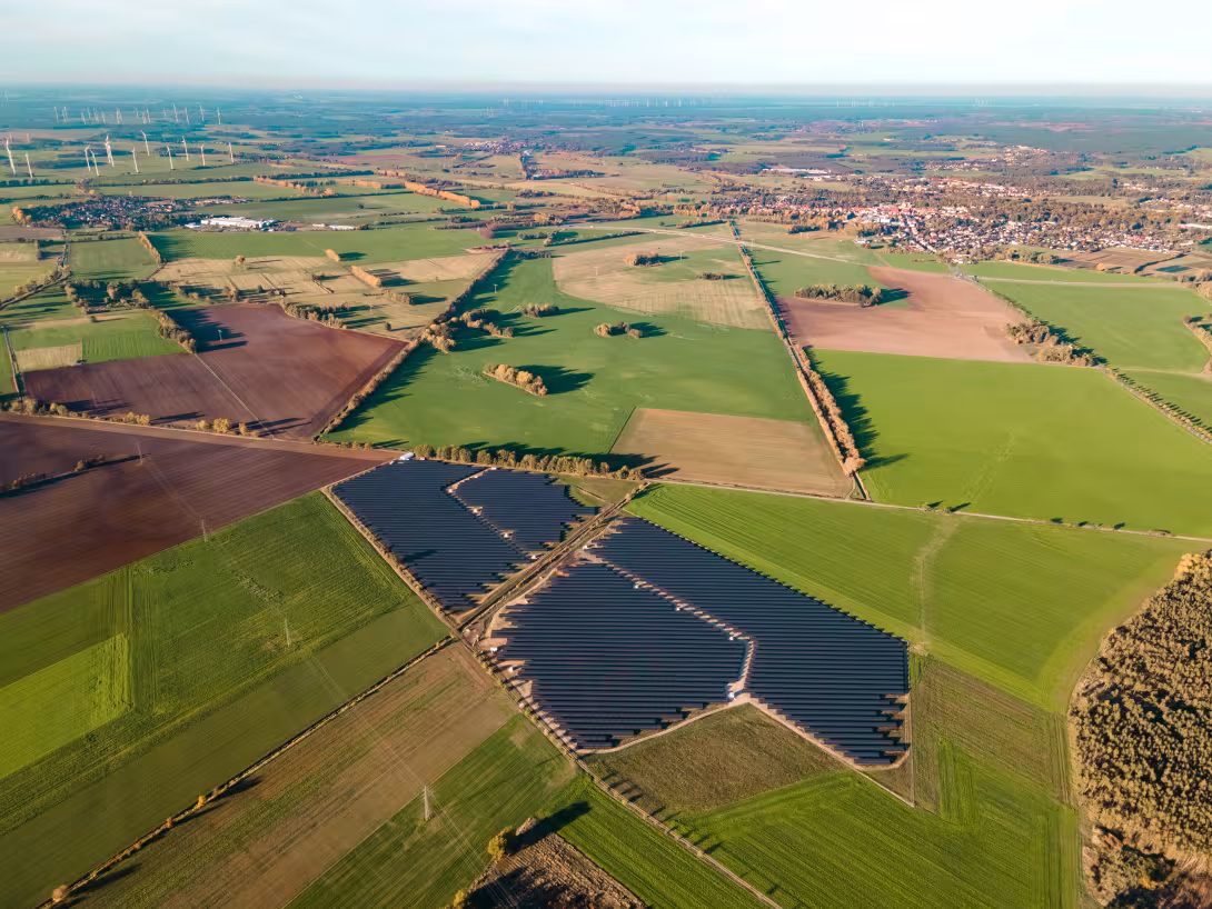 Luftaufnahme einer Landschaft mit Feldern und einem großen Solarpark in der Mitte