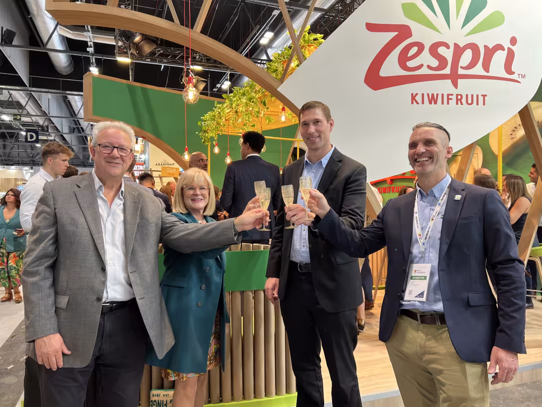 Tim Watkins (Sinclair), Paola Verzello (Sinclair), Zespri-CEO Jason Te Brake und Duncan Jones (Sinclair) stehen am Zespri-Messestand und prosten sich mit Sekt zu.